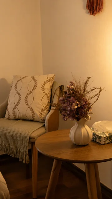 Poltrona com almofadas e arranjo de flores secas na recepção